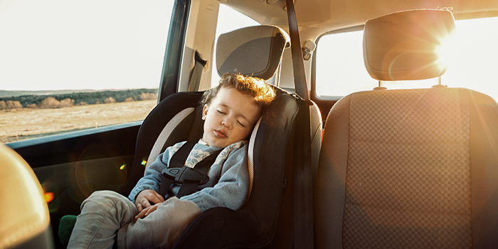 Bambino che dorme in auto con il sole che illumina dietro